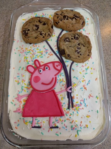 Cake with Peppa Pig drawn on it with cookies as balloons