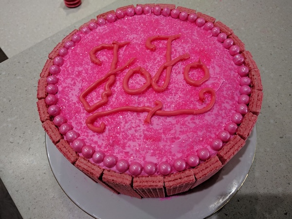 Pink frosted cake with various pink-themed candies