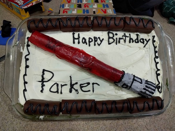 Cake with a red lightsaber made of fruit-roll-up wrapped cake rolls